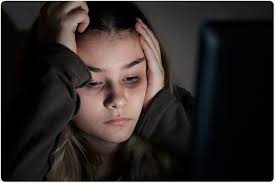 Girl with dark circles looking at a laptop screen